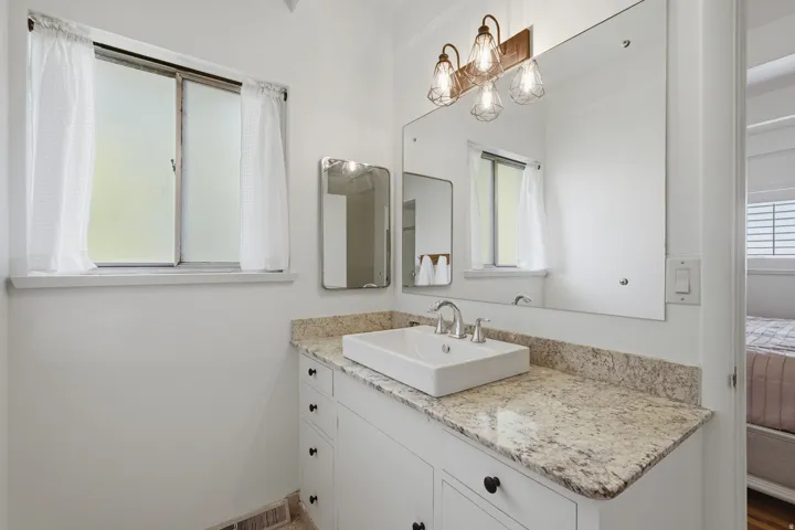Primary bathroom.  White vanity with multiple drawers and cabinet storage, rectangular vessel sink, and a speckled countertop