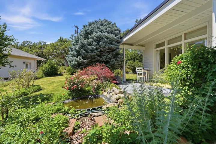 Expansive backyard featuring a manicured lawn, established landscaping, and a tranquil water feature