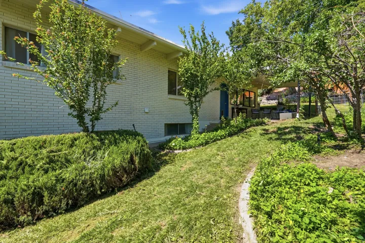 White brick exterior, established landscaping, mature trees, and a covered patio