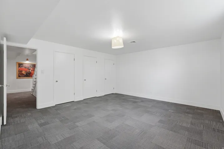 Bedroom #4.  Spacious room with gray patterned carpet flooring, white walls, and multiple white panel doors