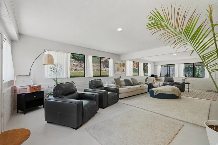 Recessed lighting, painted brick accent wall, multiple windows with a ground-level exterior, and light-colored flooring
