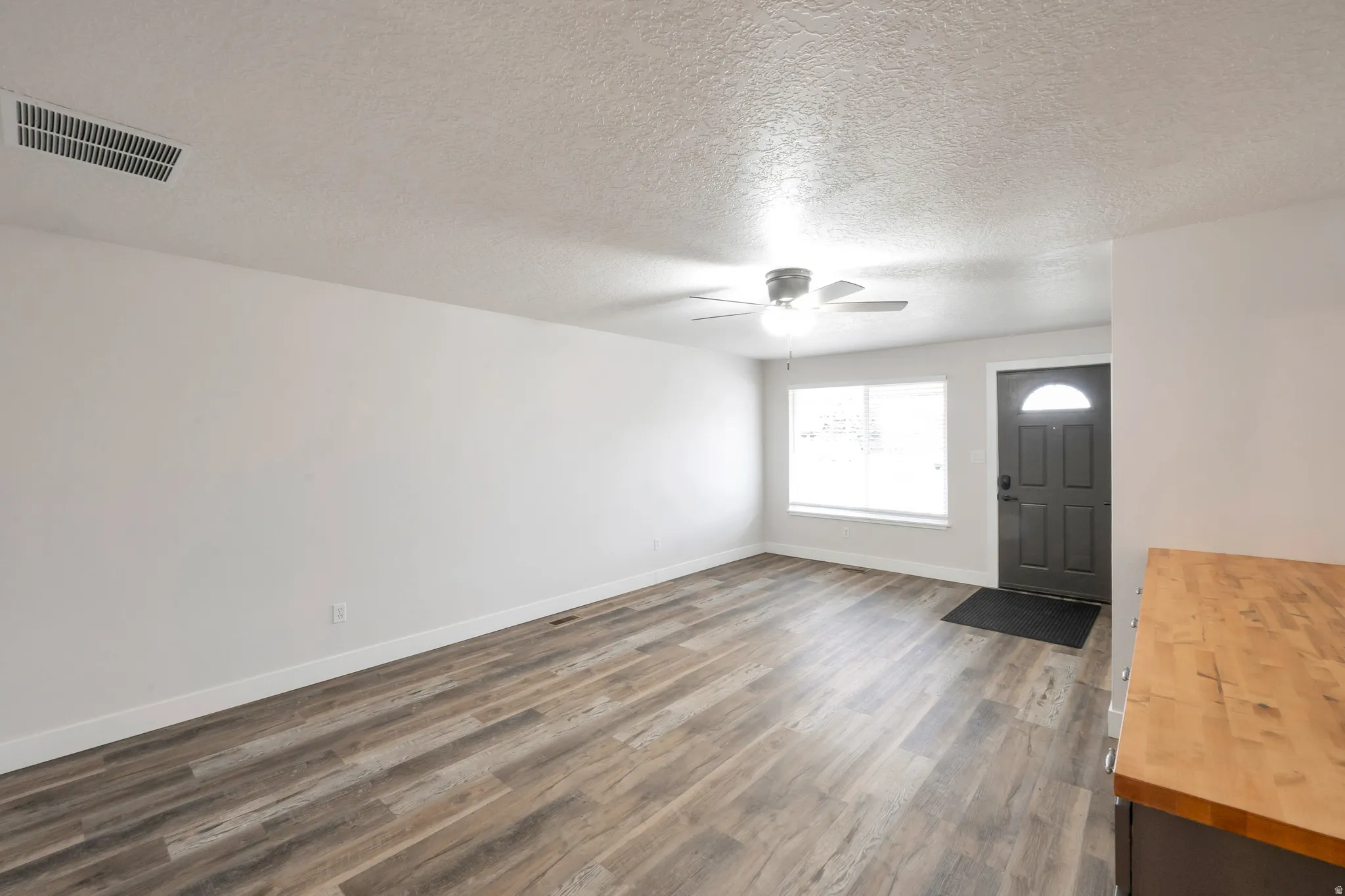 Wood-finish flooring, white walls, and a ceiling fan with integrated lighting