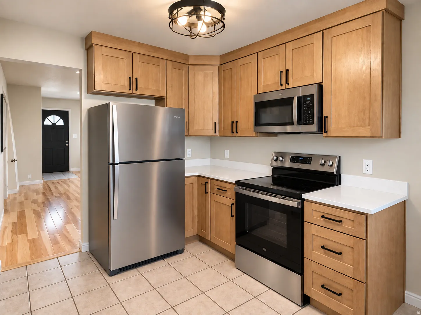 Kitchen featuring light wood cabinetry, stainless steel appliances, white countertops, and tiled flooring