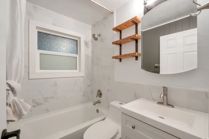 White tile shower surround with a built-in tub and a window featuring obscured glass