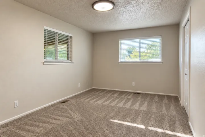Neutral-toned walls complement the textured carpet flooring