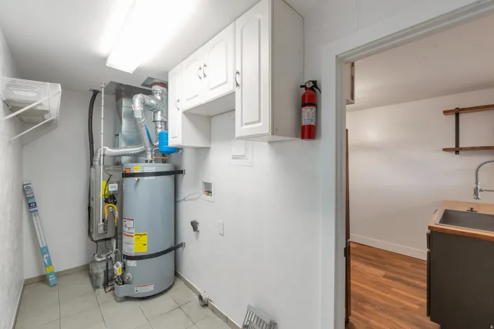 Utility area with tiled flooring, white upper cabinetry, and a ceiling-mounted fluorescent light fixture