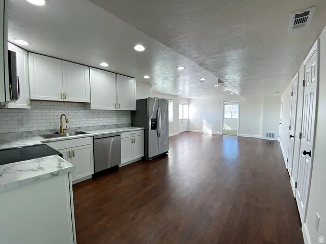 Kitchen featuring white cabinetry, subway tile backsplash, stainless steel appliances, and wood-finish flooring