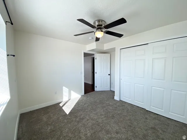 Plush carpeting, bright white walls, and a ceiling fan with integrated lighting