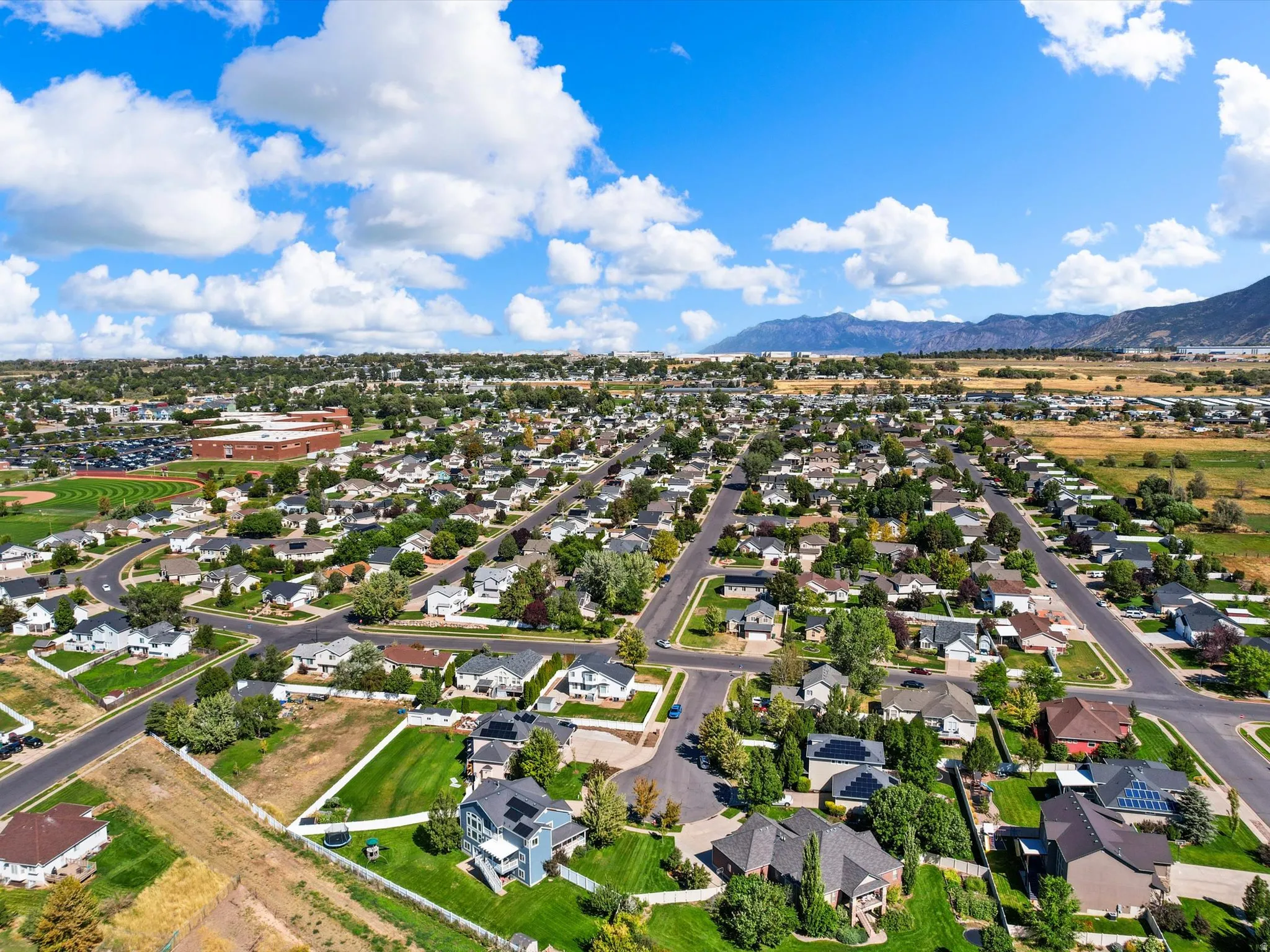 Expansive residential area featuring numerous single-family homes with pitched roofs, mature trees, and paved streets