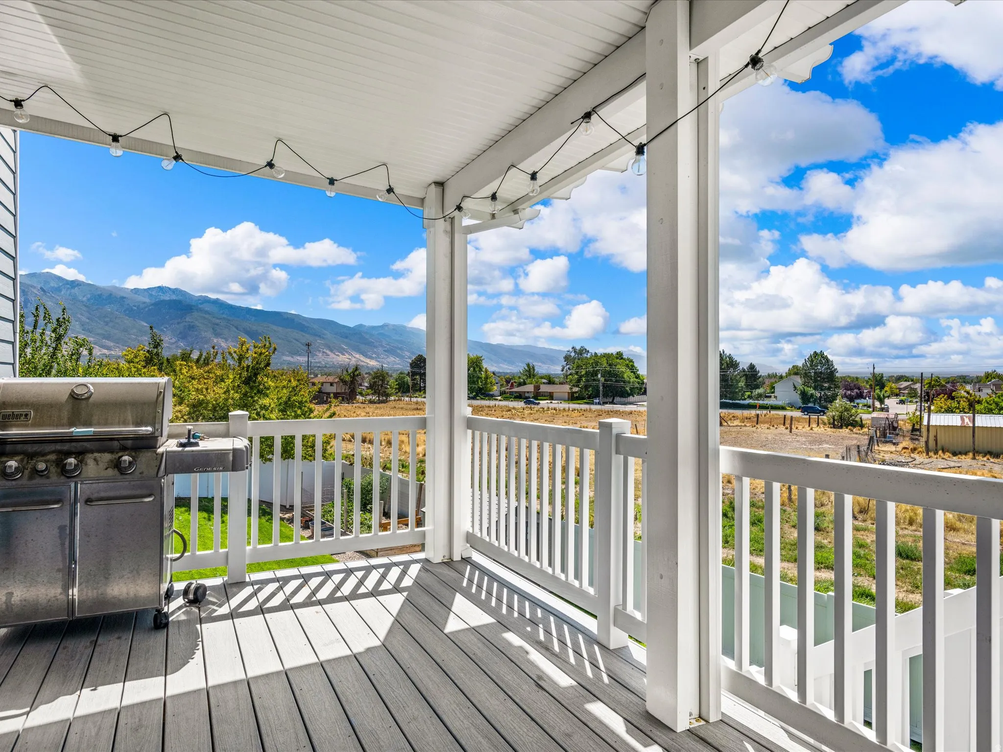 Covered porch featuring wood-finish decking, white balustrade, and recessed lighting