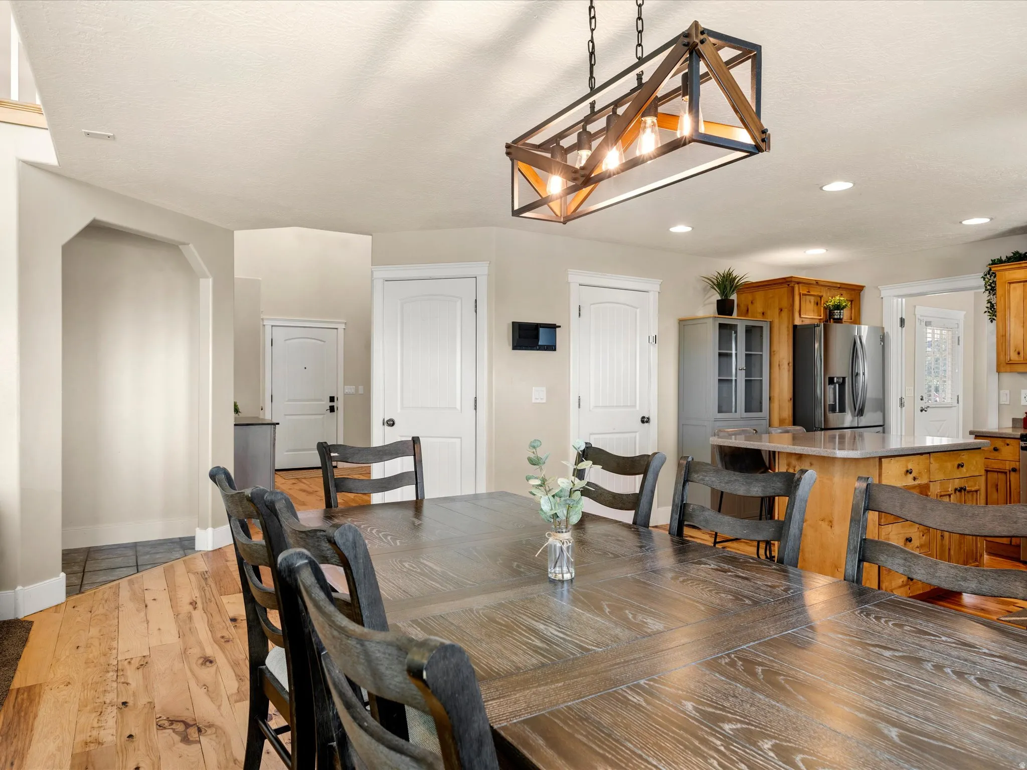 Wood-finish flooring, recessed lighting, and a linear chandelier with a metal and wood frame