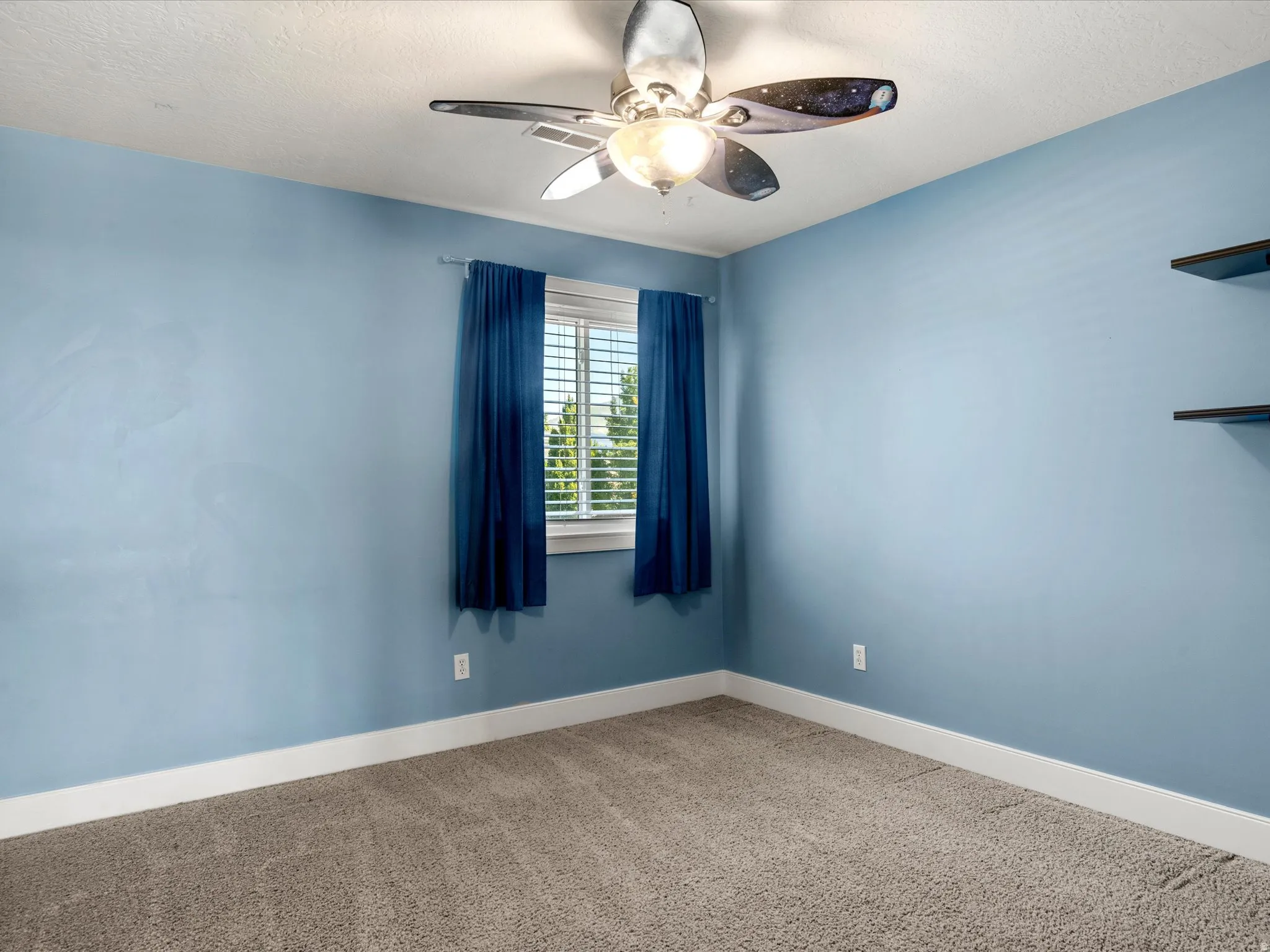 Recessed window with white blinds, wall-mounted shelving, and a ceiling fan with integrated lighting