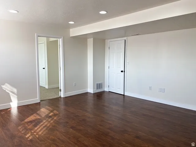 Recessed ceiling lighting, wood-finish flooring, crisp white walls, white trim, and a white paneled door