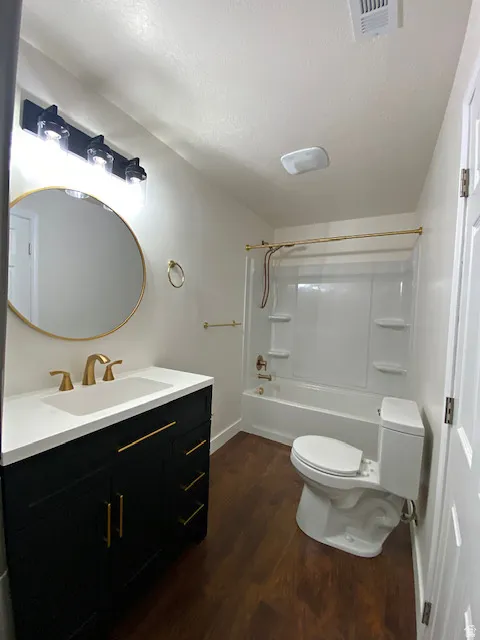 Dark wood-finish flooring with a white vanity featuring gold-tone hardware