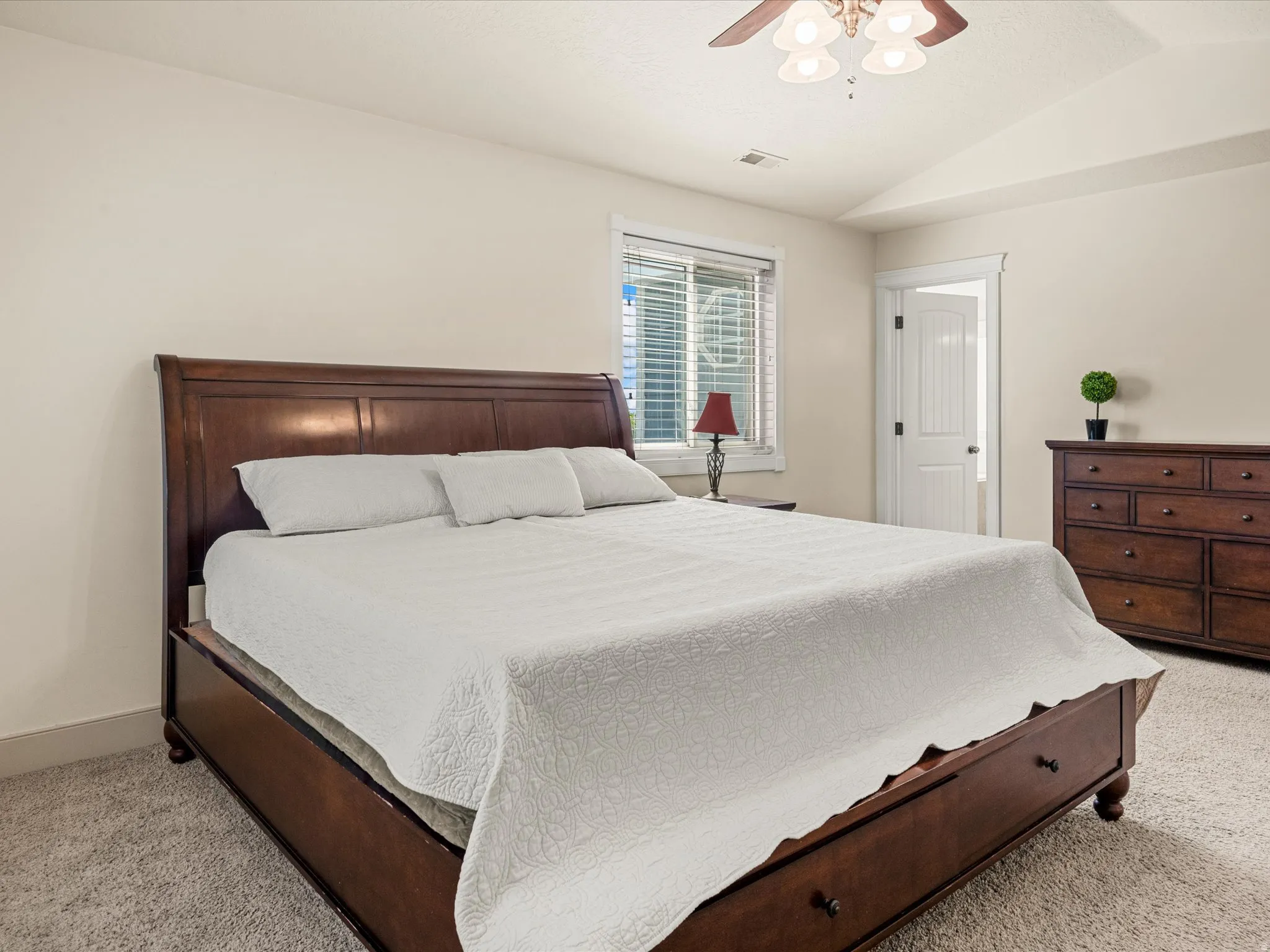 Soft carpeting, neutral wall tones, window with blinds, and a ceiling fan with integrated lighting
