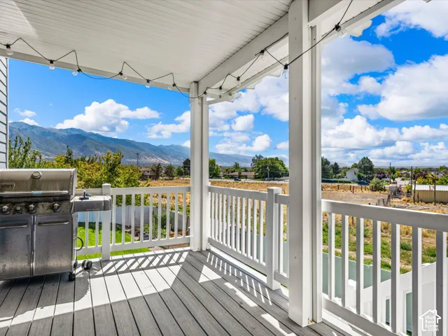 Covered porch featuring wood-finish decking, white balustrade, and recessed lighting