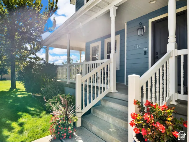 Covered front porch with white railings and balusters, concrete steps, and a blue exterior facade with white trim
