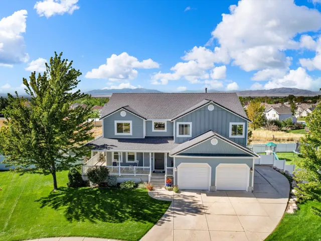 Two-story residence featuring light blue siding, a dark roof, an attached two-car garage, and a covered porch