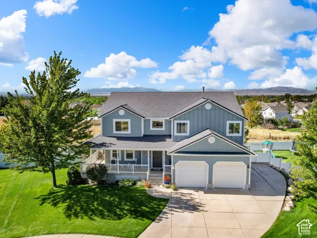 Two-story residence featuring light blue siding, a dark roof, an attached two-car garage, and a covered porch