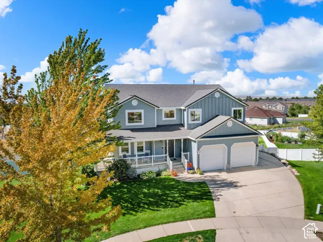 Two-story residence with light blue siding, a dark gray roof, a covered front porch with white railings, a two-car garage, and a concrete driveway
