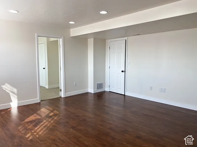Recessed ceiling lighting, wood-finish flooring, crisp white walls, white trim, and a white paneled door