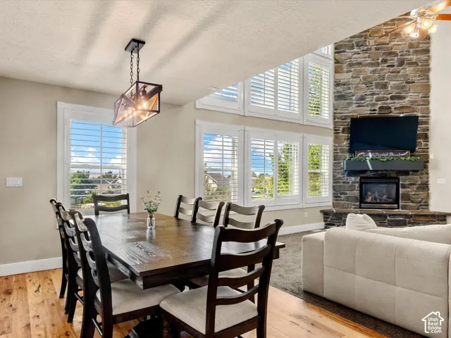 Hardwood-finish flooring, a contemporary chandelier, a stone-clad fireplace with a gas insert, and multiple windows with plantation shutters