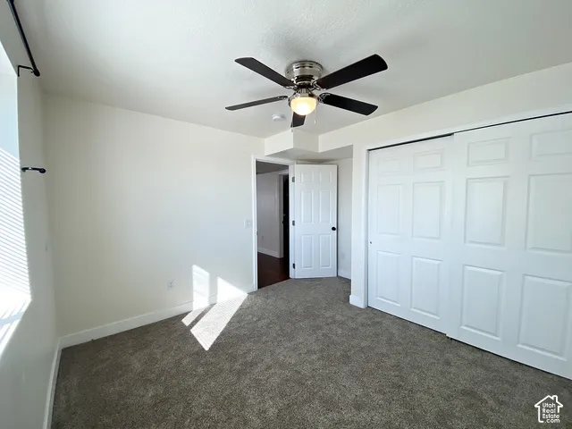 Plush carpeting, bright white walls, and a ceiling fan with integrated lighting