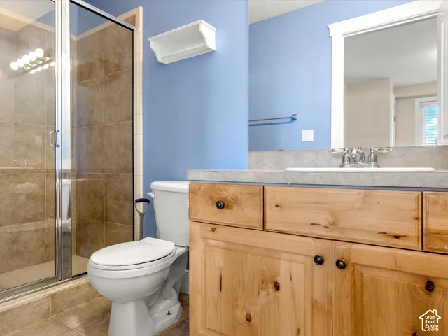 Glass-enclosed shower with tile surround, wood-finish vanity with ample storage, integrated sink, and framed mirror