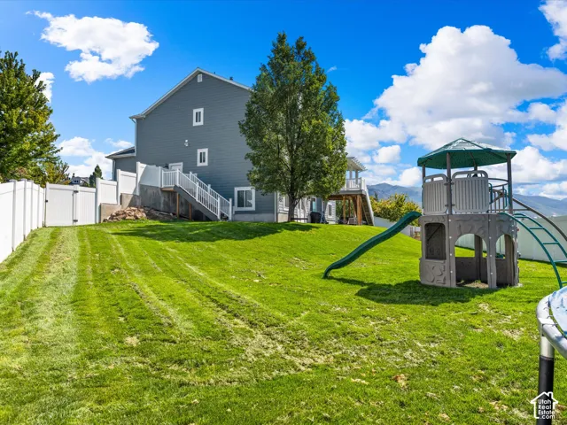 Expansive grassy yard with a multi-level deck and white privacy fencing
