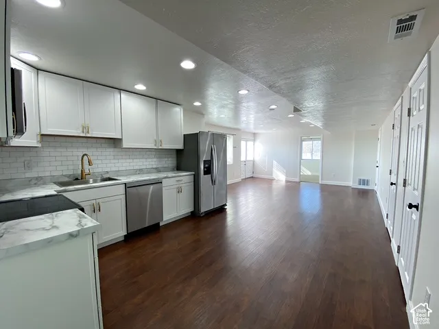 Kitchen featuring white cabinetry, subway tile backsplash, stainless steel appliances, and wood-finish flooring