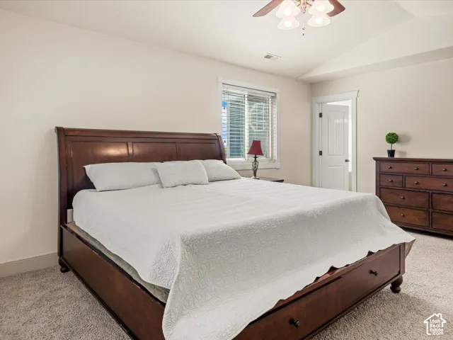 Soft carpeting, neutral wall tones, window with blinds, and a ceiling fan with integrated lighting
