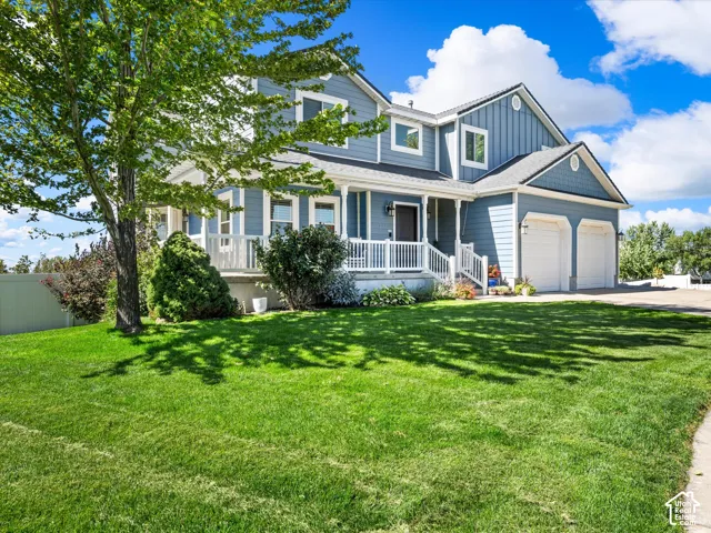 Two-story residence featuring light blue siding, a covered front porch with white railings, and an attached two-car garage