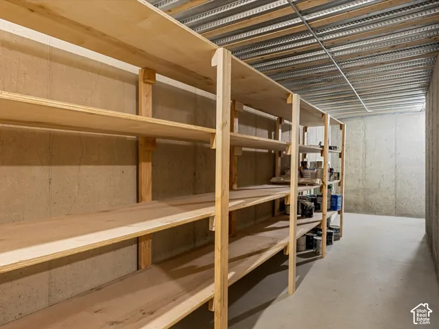 Extensive wood shelving units, concrete walls, concrete flooring, and an exposed metal ceiling