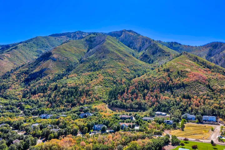 Expansive mountain backdrop with varied foliage and a scattered residential area