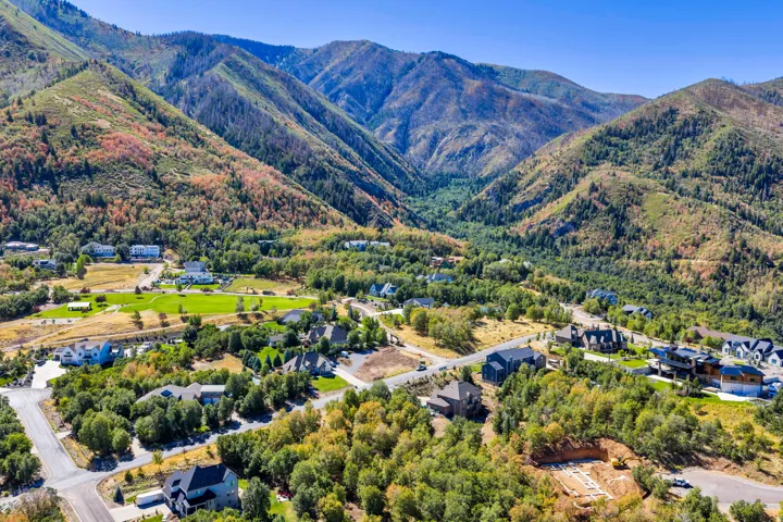 Mountainous terrain backdrop, residential development, established landscaping, paved roads, and building under construction