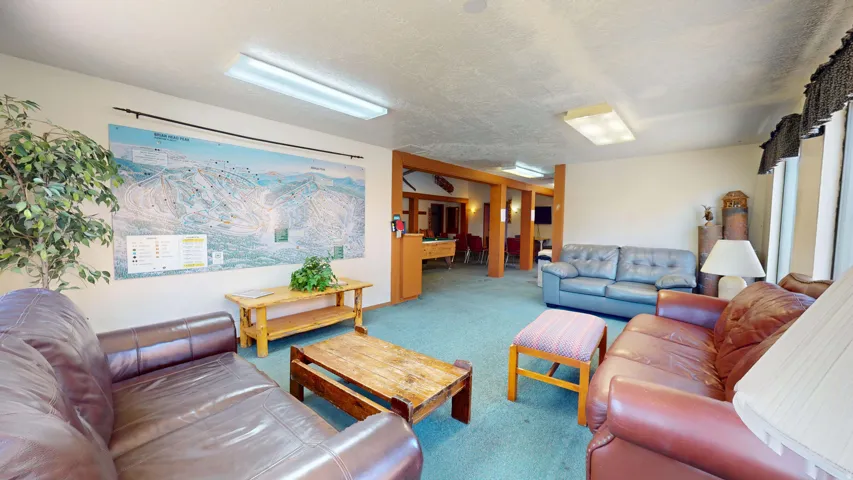 Open common area with light blue carpet, wood-finish columns, and recessed lighting fixtures