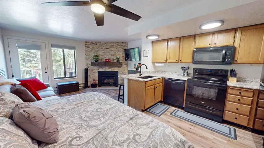 Compact kitchen with wood cabinetry, black appliances, and light-toned countertops