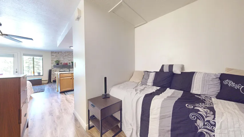 Wood-finish flooring, white walls, and a ceiling fan