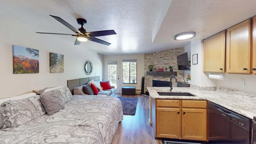 Open concept living space featuring wood-finish flooring, a stone accent wall, and recessed lighting