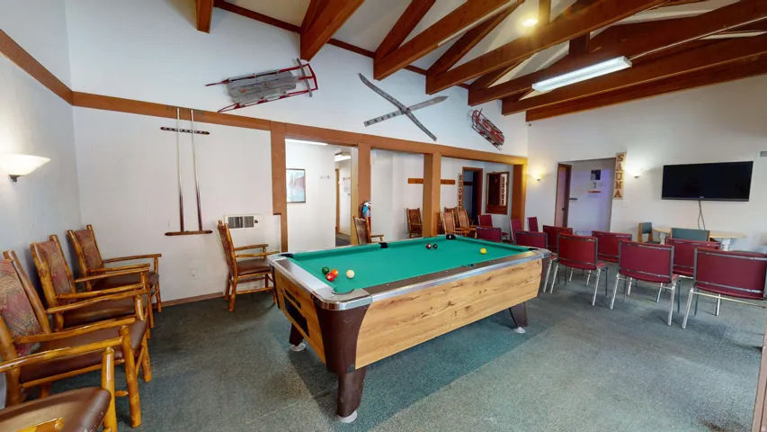 Recreational area featuring a pool table, exposed wood ceiling beams, and wall-mounted sconces