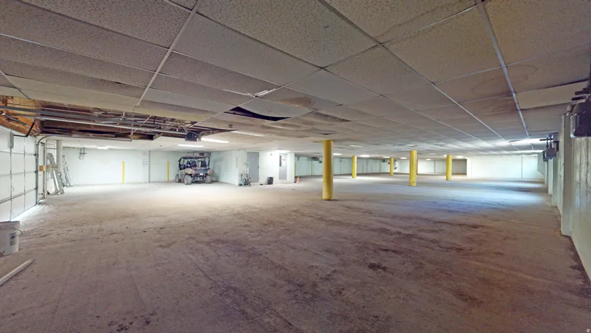 Expansive interior space with multiple support columns, industrial lighting, and a roll-up door