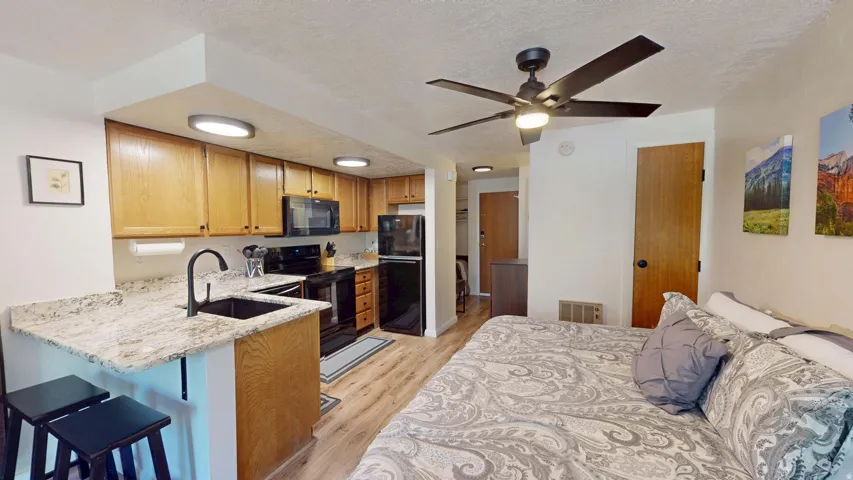 Kitchenette with granite-finish countertops, wood-finish cabinetry, and black appliances