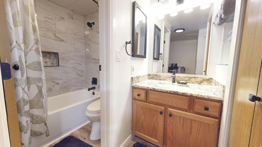 Bathroom featuring a vanity with a granite countertop, wood-finish cabinetry, and a large wall mirror