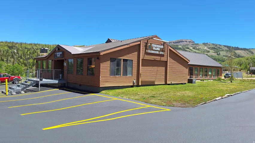 Clubhouse structure with horizontal wood siding, multiple windows, and a metal roof