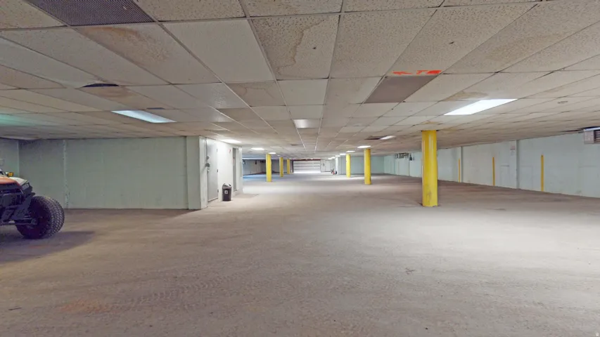 Expansive interior space featuring concrete flooring, drop ceiling with integrated lighting, and multiple structural columns