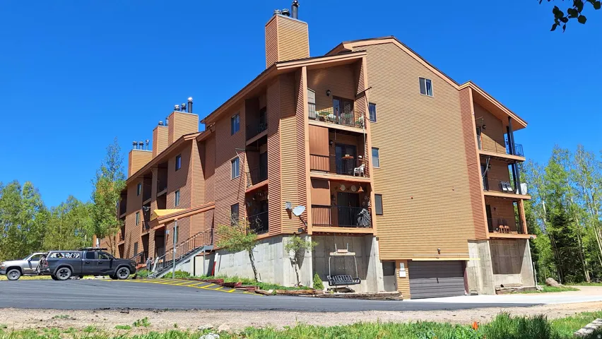 Multi-story building featuring balconies with metal railings, a concrete foundation, and an attached garage door