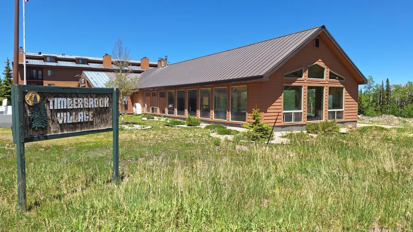 Building featuring a brown metal roof, wood siding, and large windows