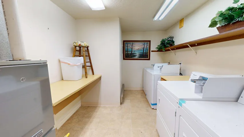 Built-in shelving, two sets of white laundry appliances, and a utility counter