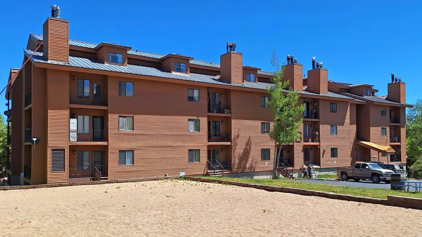 Multi-story building featuring a brown siding exterior, numerous private balconies, and a metal roof