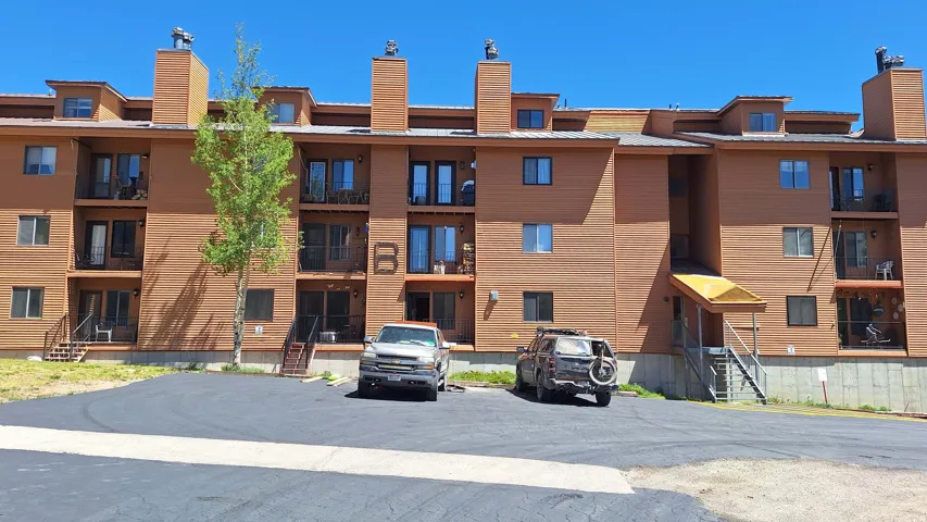 Brown horizontal siding exterior with multiple balconies, dormer windows, and prominent chimneys